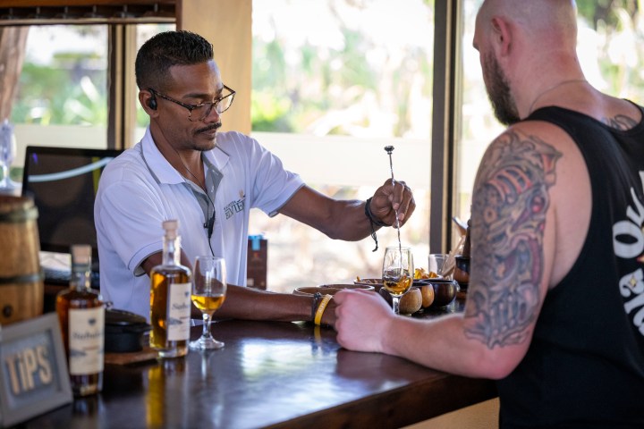 Bartender serving drinks to a man at a bar counter.