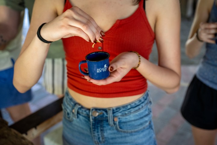 Person in red top holding a small blue coffee cup indoors.