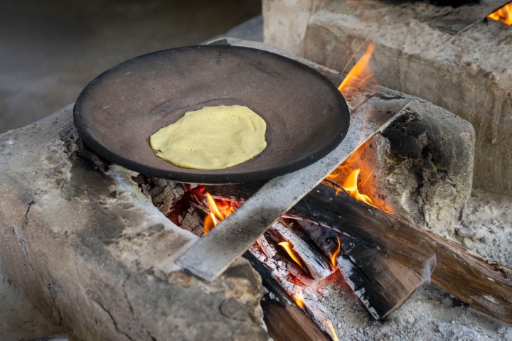 Tortilla cooking on a hot pan over an open fire.