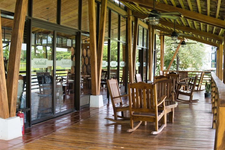 Wooden porch with rocking chairs and glass doors overlooking a green landscape.