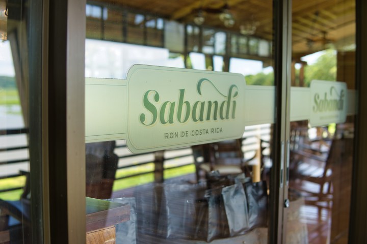 Glass door with Sabandi logo and outdoor view reflection.