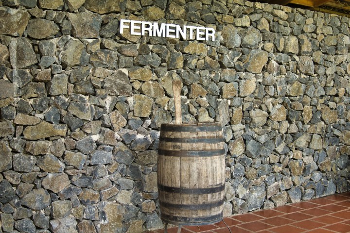 Stone wall with 'FERMENTER' sign above a wooden barrel.