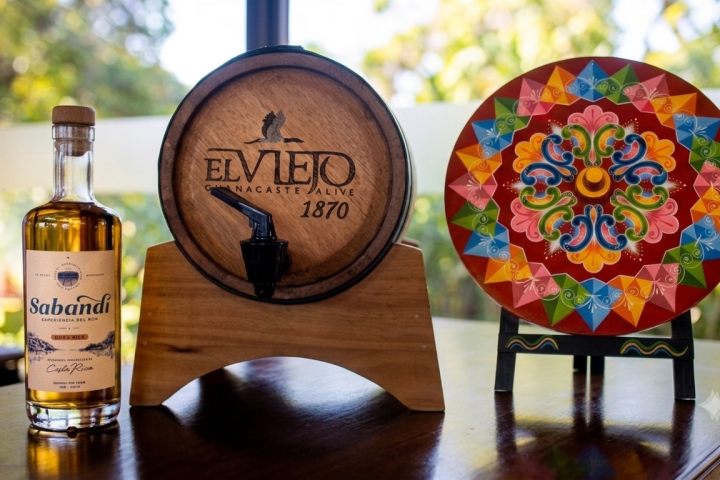 Bottle, wooden barrel, and colorful plate on display.