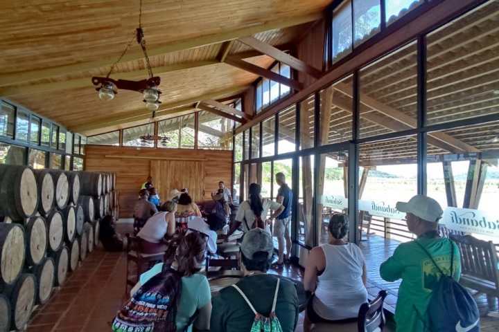 Group tours a rustic winery with wooden barrels and high ceilings.