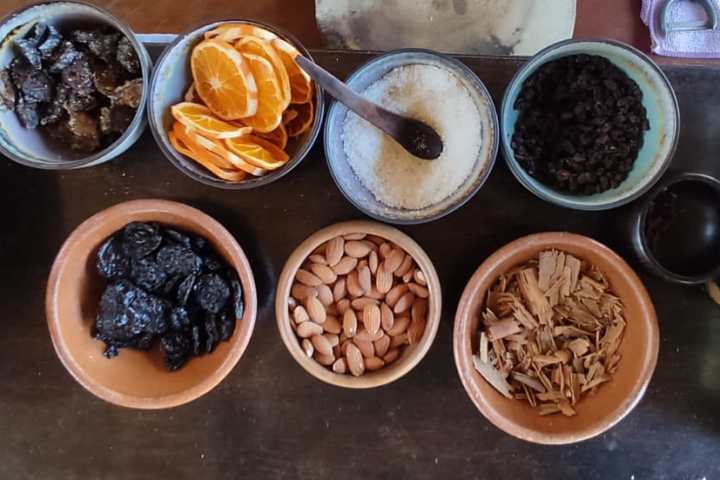 Variety of nuts, dried fruits, chips, and seasonings in bowls on a table.
