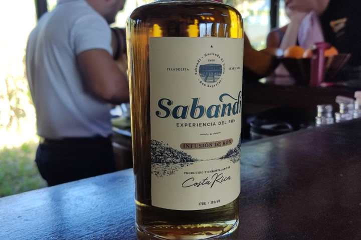 Bottle of Sabandí rum on bar counter, people in background.