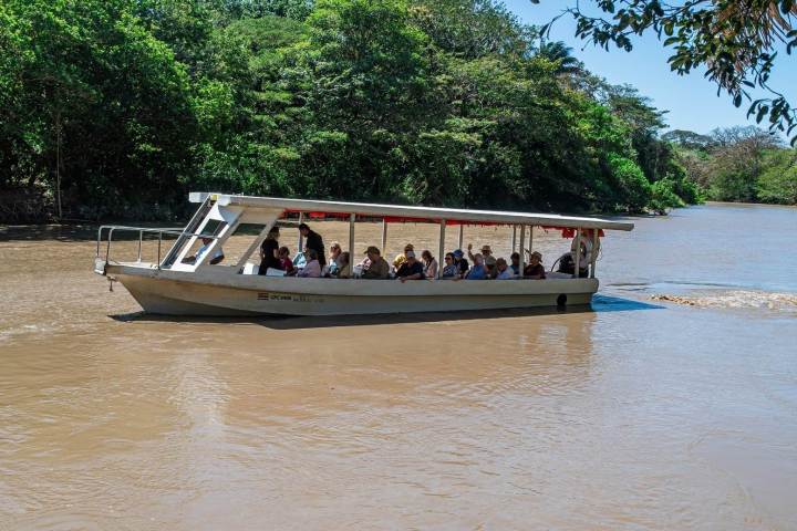 a boat floating along a river next to a body of water
