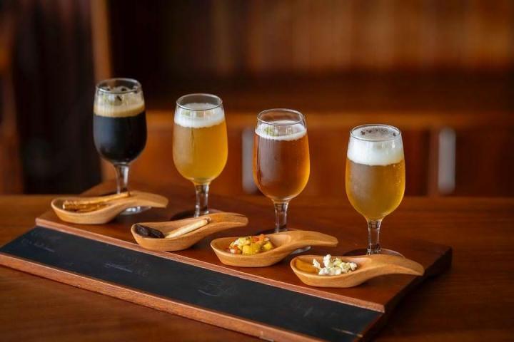 a glass of beer on a wooden table topped with glasses of wine