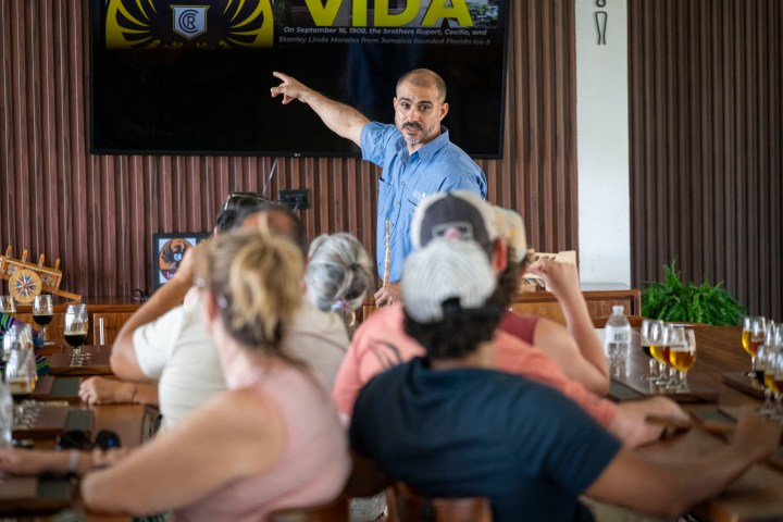 Man giving presentation to seated group in a room with wooden decor.