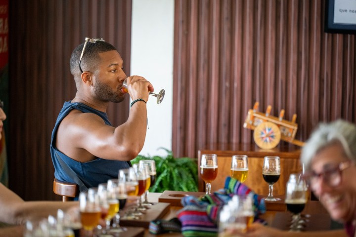 Man tasting beer in a bar with multiple glasses on the table.
