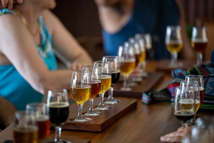 People sit with multiple glasses of beer on a wooden table.