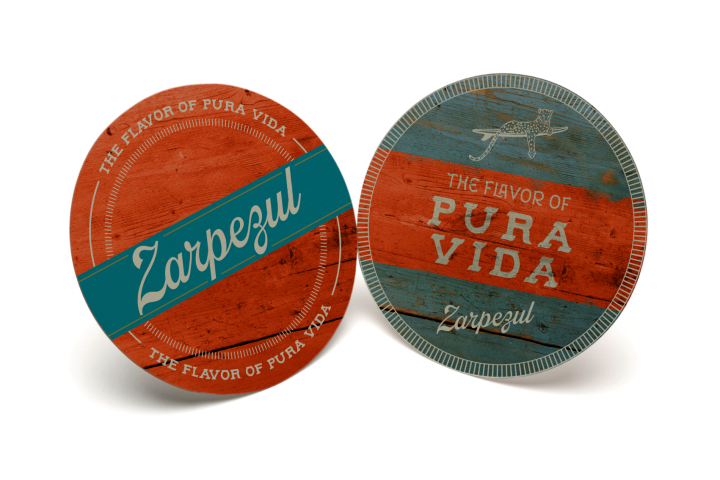 Two round coasters with 'The Flavor of Pura Vida' and 'Zarpezul' text, featuring wood-like textures.