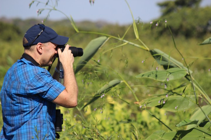 Man in blue shirt photographing nature with a camera.