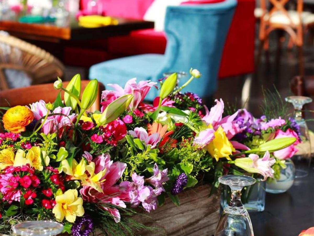 Colorful flower centerpiece on a dining table with chairs.
