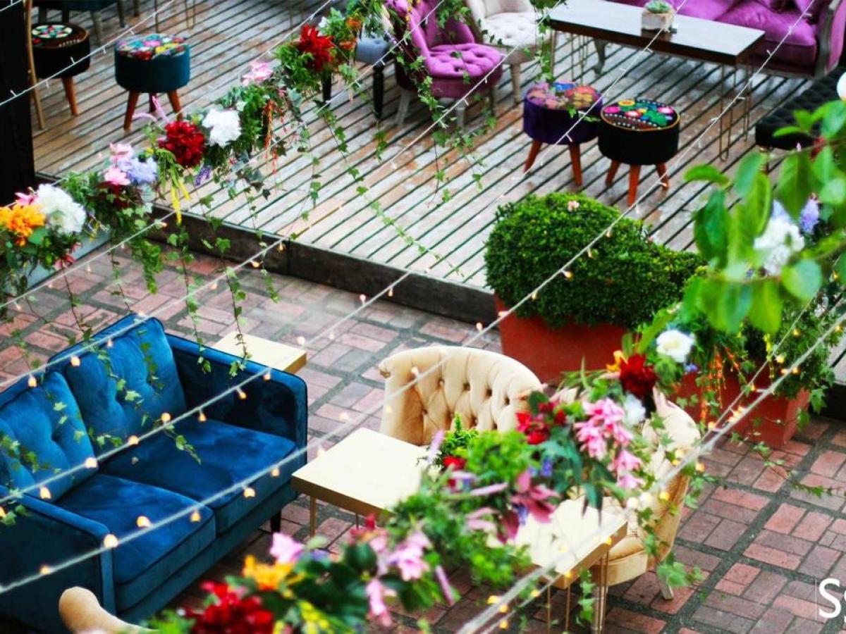 Vibrant outdoor seating with colorful sofas and floral decorations.