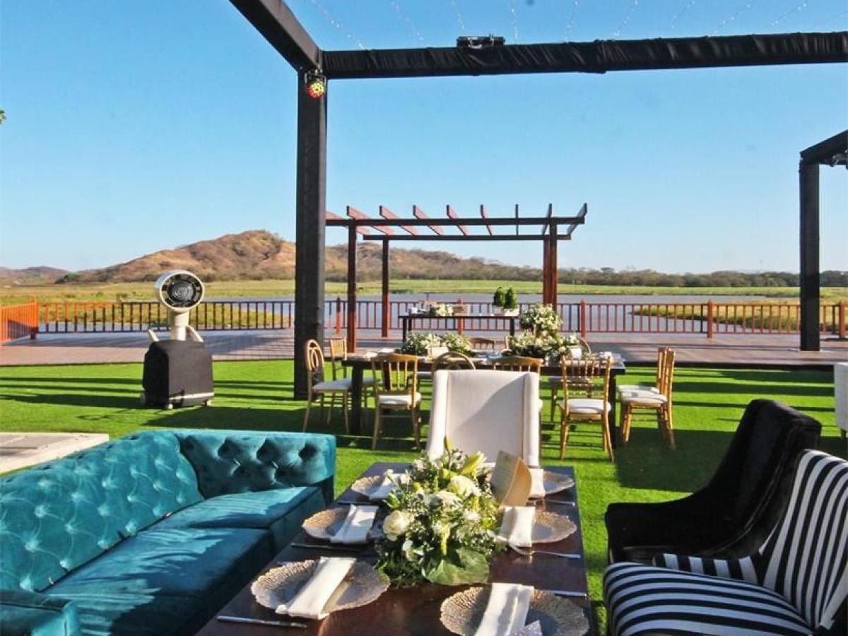 Outdoor dining with a blue sofa, striped chair, and mountain view.