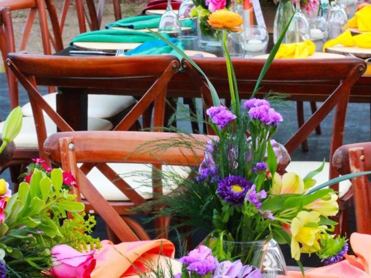 Outdoor event with colorful floral centerpieces and table settings.