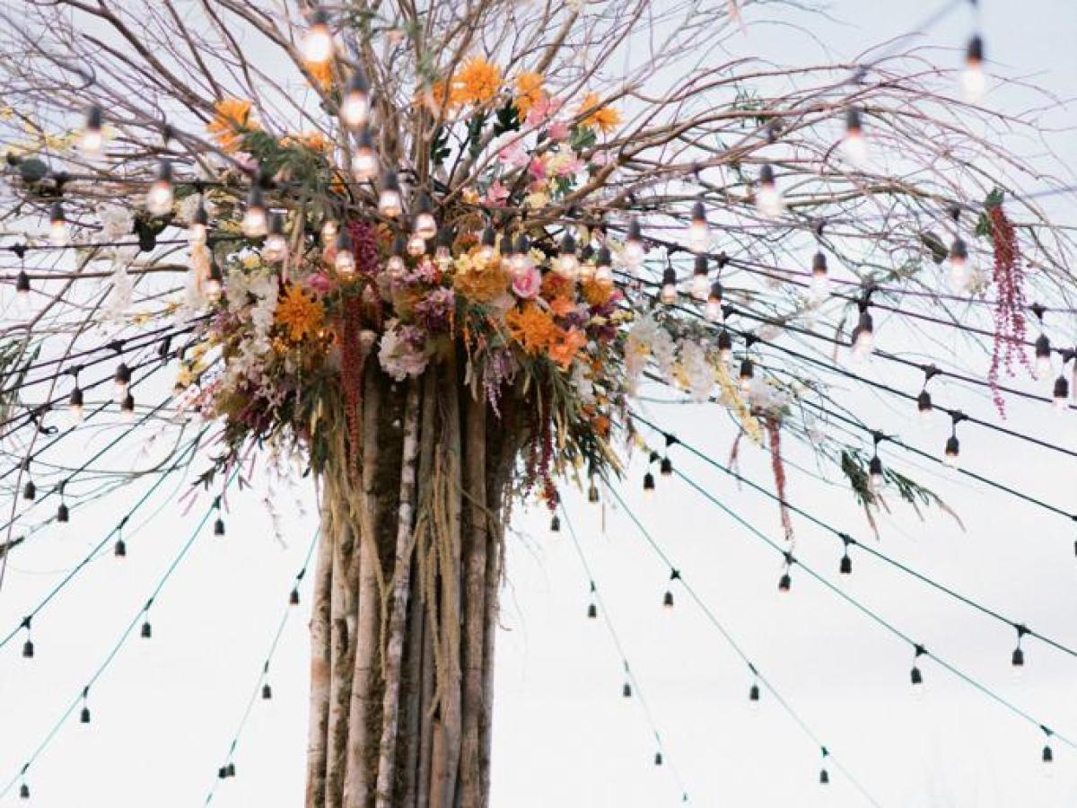 Tall wooden poles arranged with hanging lights and flowers.