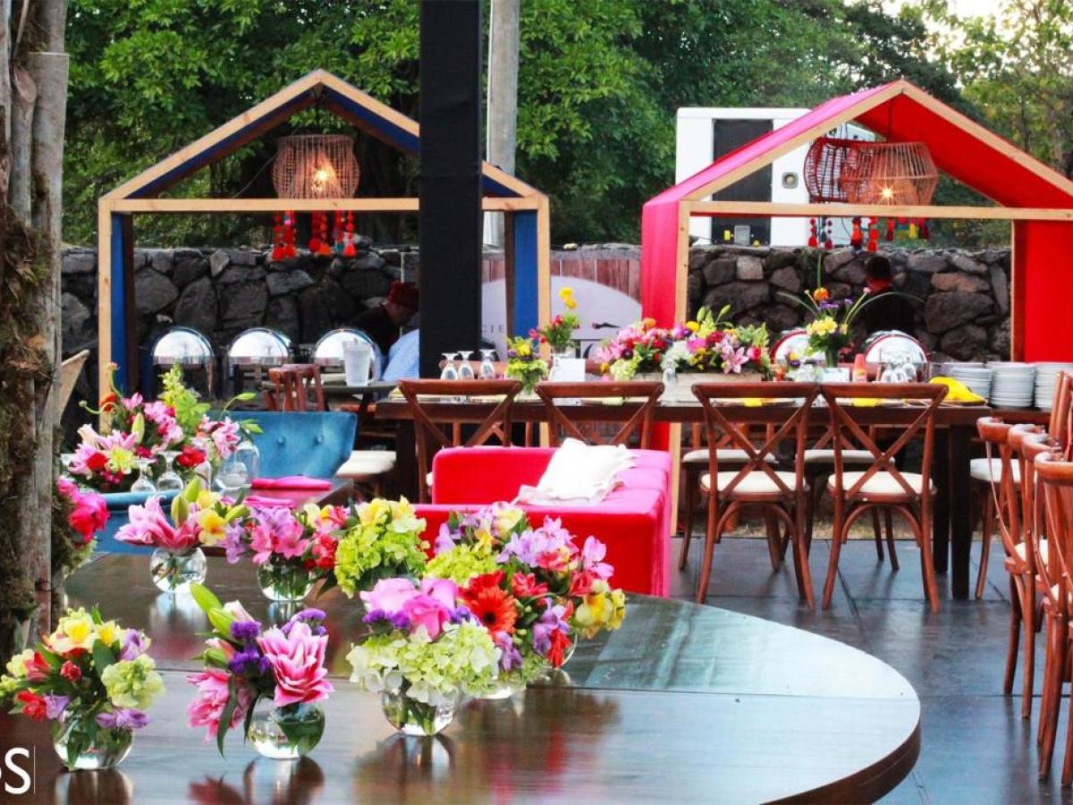 Outdoor dining area with colorful flowers and canopy structures.