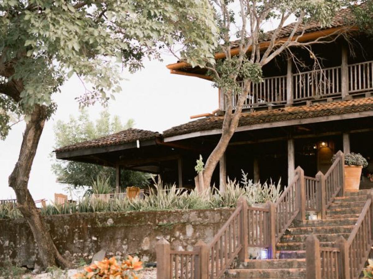 Rustic house with wooden stairs, trees, and wagon wheels decor.