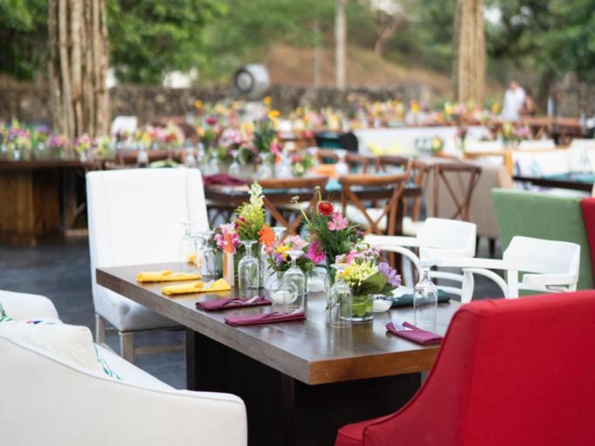 Outdoor dining setup with colorful chairs and string lights.