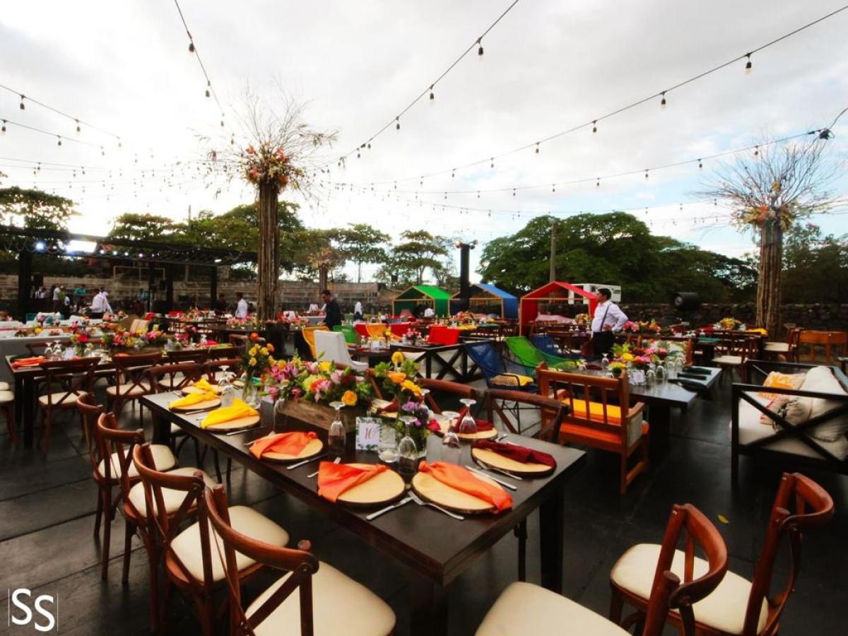 Outdoor event setup with decorated tables, string lights, and colorful centerpieces.