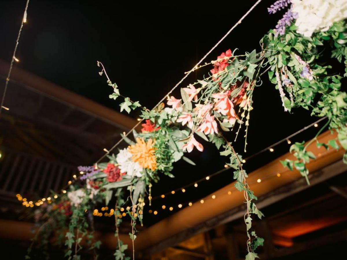 String lights and floral garlands under a dark sky.