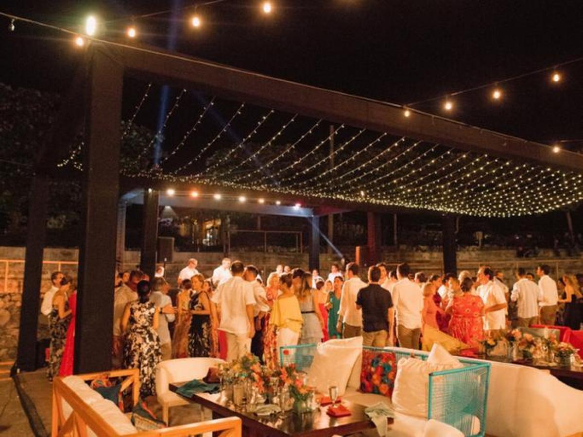 Outdoor evening event with people mingling under string lights.
