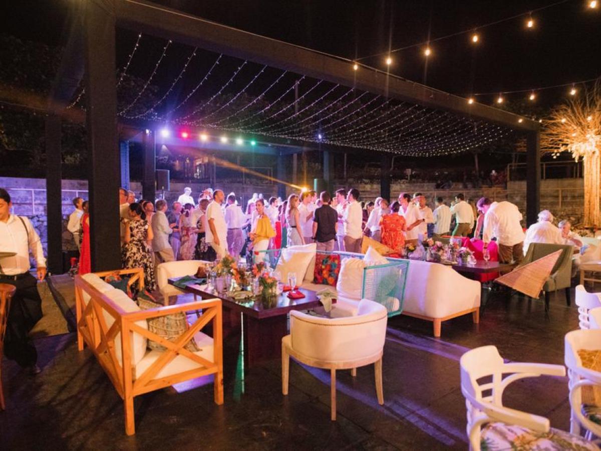 Outdoor nighttime party with people mingling under string lights.